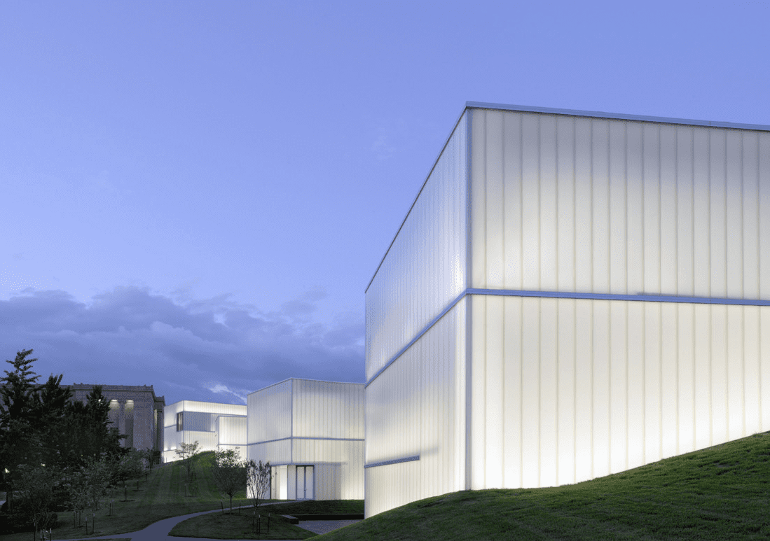 Series of opaque white glass buildings on grass.